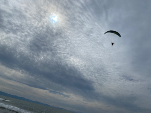 広がる雲の下を飛ぶパラグライダー